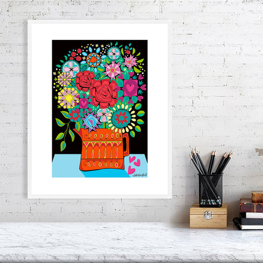 Colorful floral HAPPY CLAPPY BOUQUET by Ruth Dronsfield-art print in a white frame on a white brick wall with a desk in the foreground
