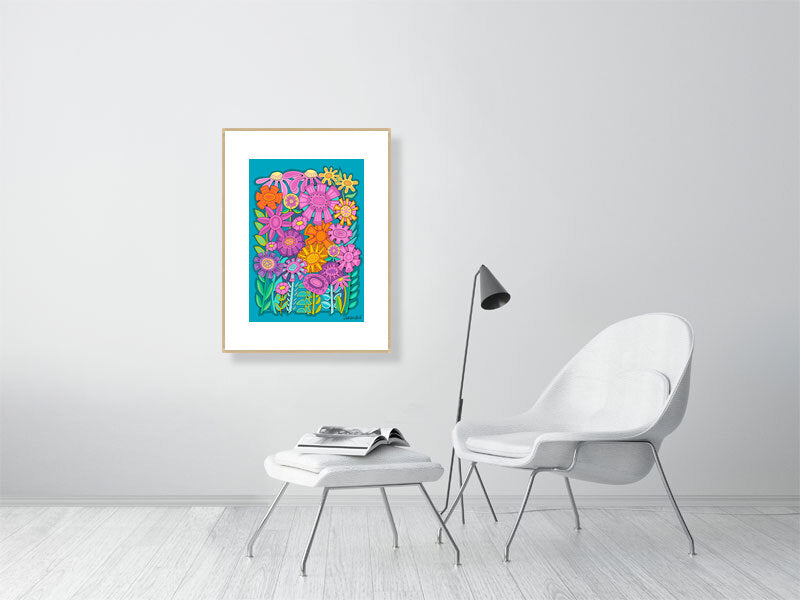 Framed floral artwork on a white wall above a white chair and ottoman.