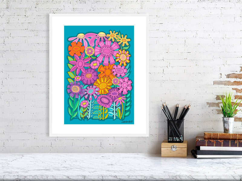 Colorful floral artwork on a white brick wall with a desk and books in the foreground.