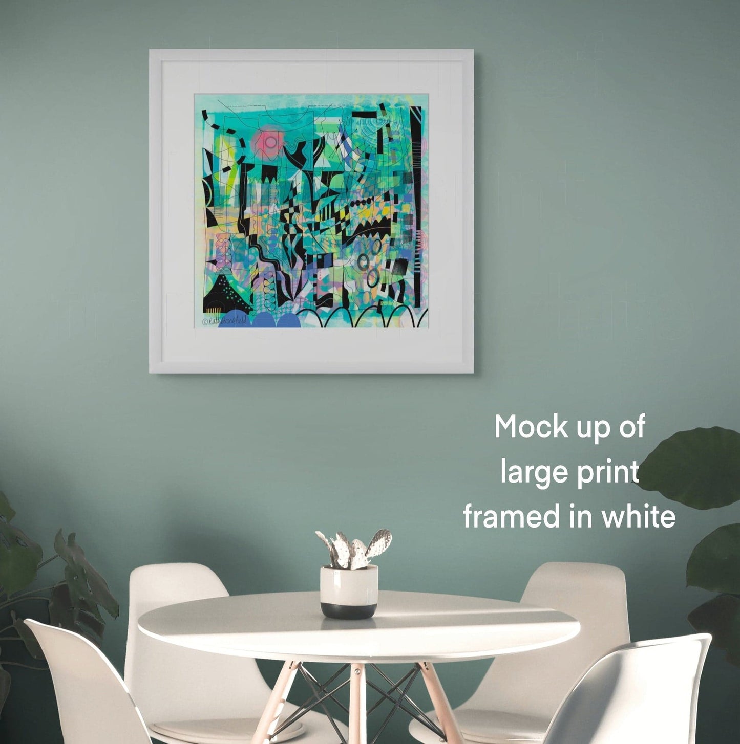 COOL GREENS Abstract Fine Art Print created from original artwork by Uk Artist Ruth Dronsfield shown in largest size framed in white frame hanging on a sage green wall with a white round dining table and four white modern dining chairs. Large houseplants are on both sides of the table