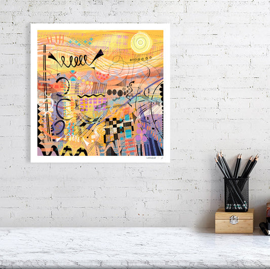 An unframed limited edition abstract art print titled 'Sunburst' by Ruth Dronsfield. The artwork features vibrant layers of yellow and orange with intricate colourful details and geometric patterns. Displayed as a square fine art print on a white brick wall.