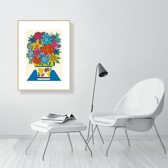 Framed colorful artwork of flowers on a wall in a modern room with a chair and lamp.