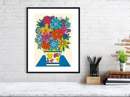 colorful floral artwork in a black frame with a white matt border on a white brick wall with desk items below.