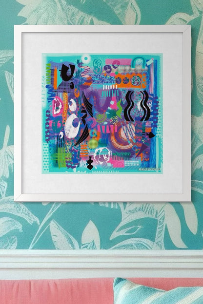 Abstract art print AFLOAT from Ruth Dronsfield Art shown framed in white hanging on a patterned wall above a pink sofa with cushions. Artwork in shades of turquoise and jade with orange,purple and pink features and black and white graphic details 