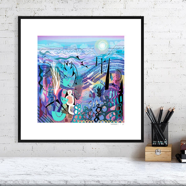A framed version of the abstract artwork 'Mauve' by Ruth Dronsfield. The intricate blue and purple print is shown mounted and finished in a clean, modern black frame with a white mount, styled on a bright wall above a white desk.