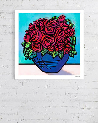 Unframed artwork of red roses in a blue vase on a white brick wall.