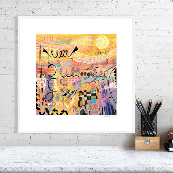 A framed limited edition abstract art print titled 'Sunburst' by Ruth Dronsfield. The vibrant yellow and orange print is professionally mounted and displayed in a clean, modern white  frame, hanging on a white brick wall above a styled marble desk.