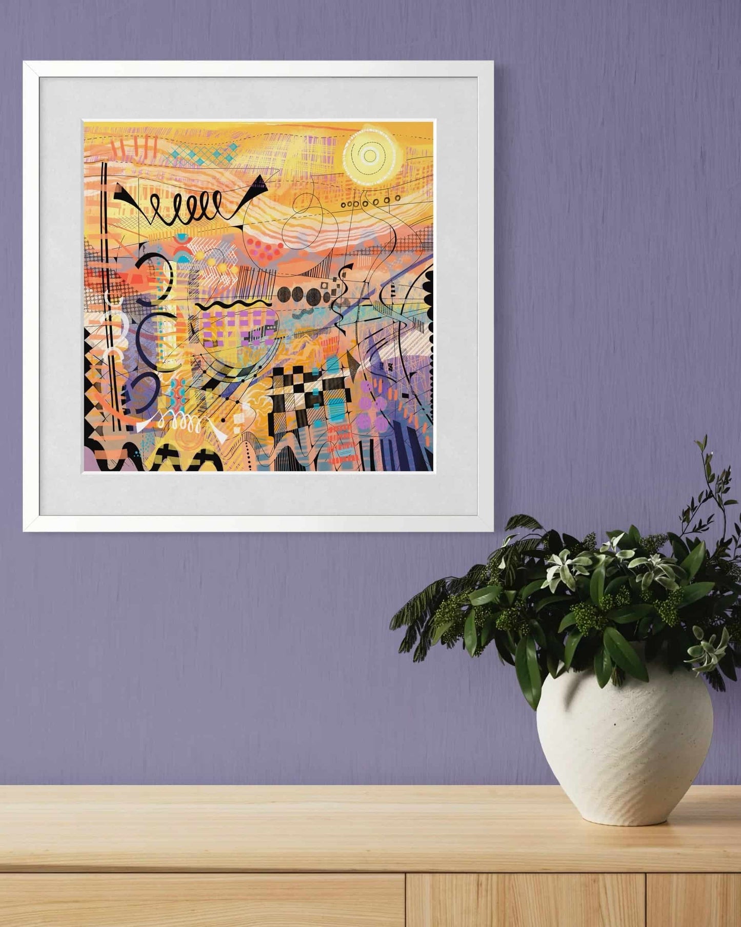 Framed Sunburst art print by UK artist Ruth Dronsfield on a purple wall with a plant below