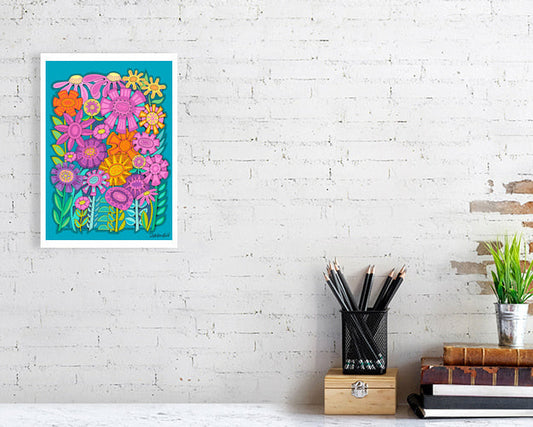 Colorful floral 'Fabulous Flowerbed' art print bu Uk artist Ruth DRonsfield. On a white brick wall above a desk with stationery items.