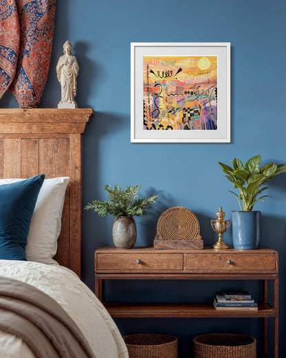 sunburst giclee art print by UK artist Ruth Dronsfield shown in a bedroom with wooden headboard, nightstand, and blue wall.