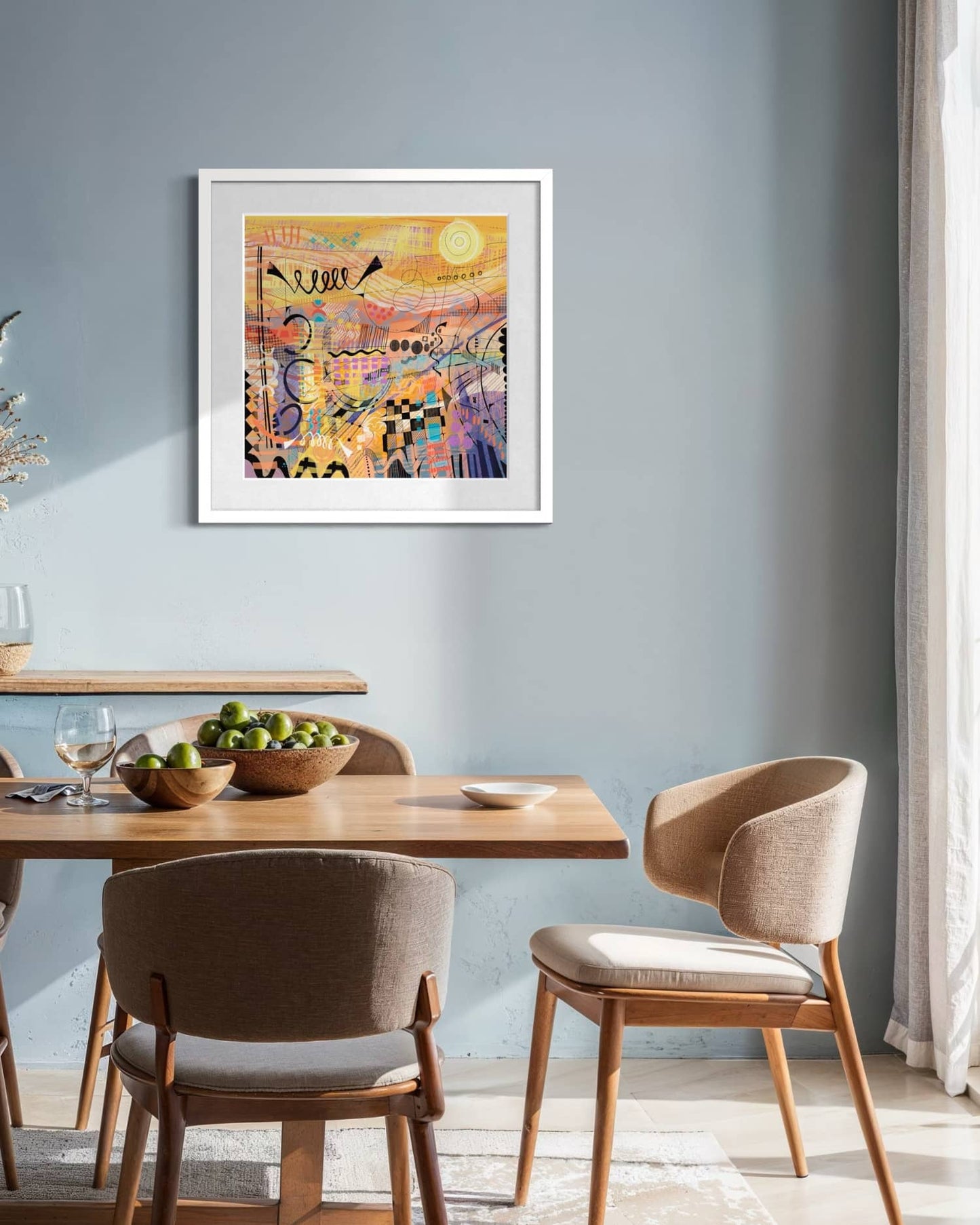 sunburst art print by UK artist Ruth Dronsfield on a grey wall in a dining room with wooden table and chairs and natural light.