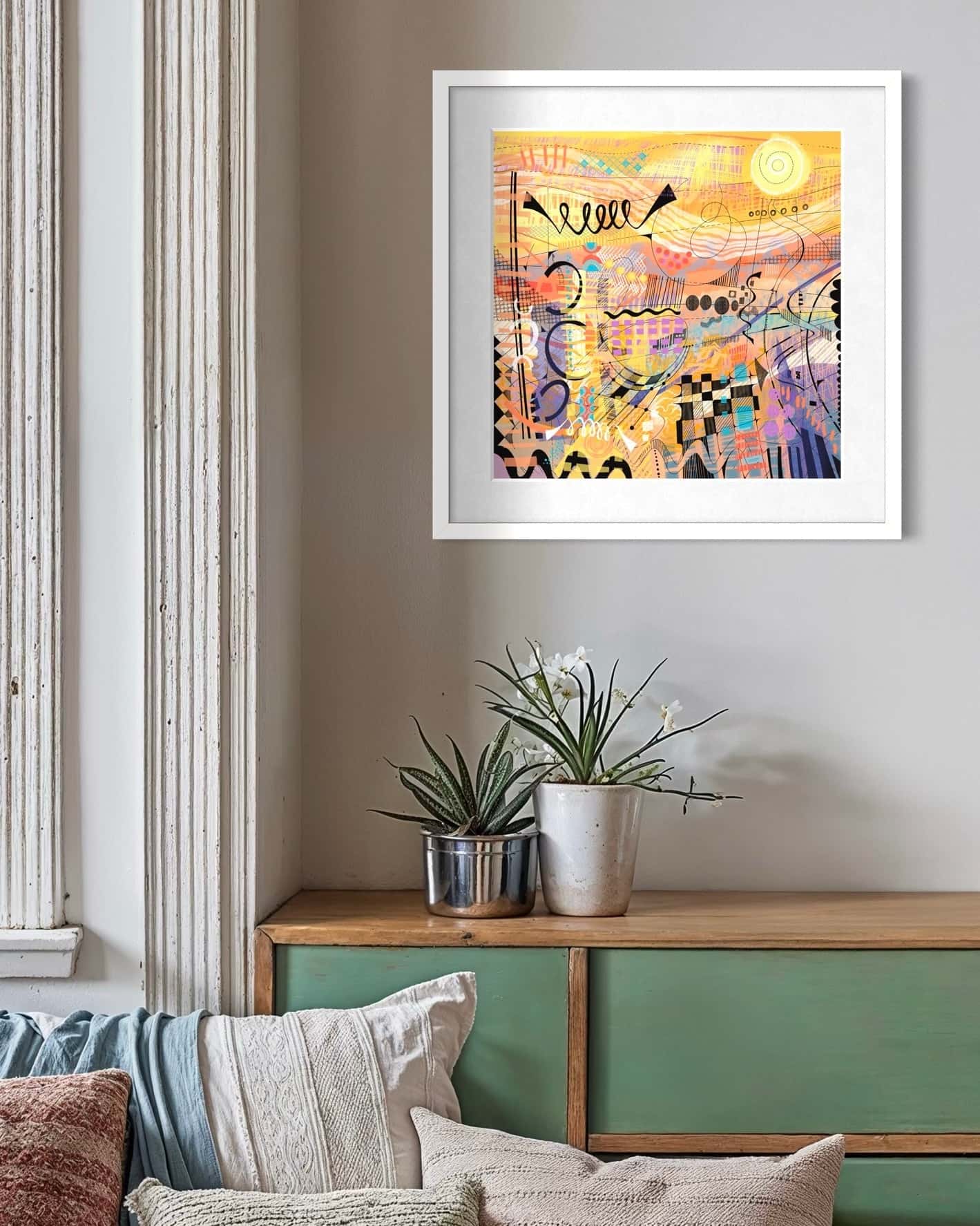 Framed Sunburst art print by UK artist Ruth Dronsfield. On a wall above a wooden console table with decorative items.